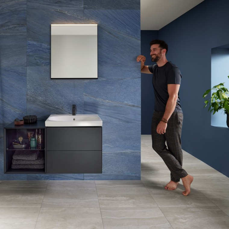 Man leaning against wall in blue bathroom with Geberit Mix & Match washplace Man leaning against wall in blue bathroom with Geberit Mix & Match washplace