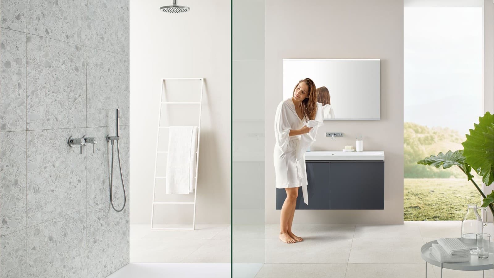 Woman drying her hair with a towel in a bathroom with open shower and large tiles in terrazzo style Woman drying her hair with a towel in a bathroom with open shower and large tiles in terrazzo style